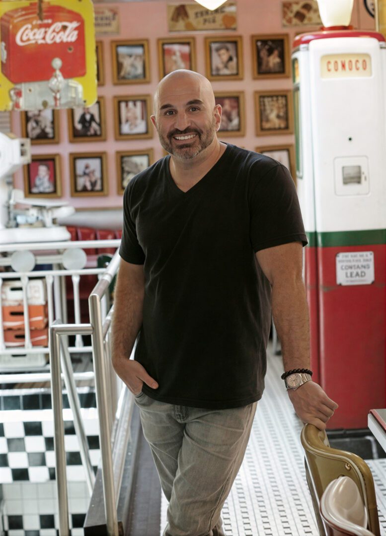 Man smiling in retro-themed diner setting.