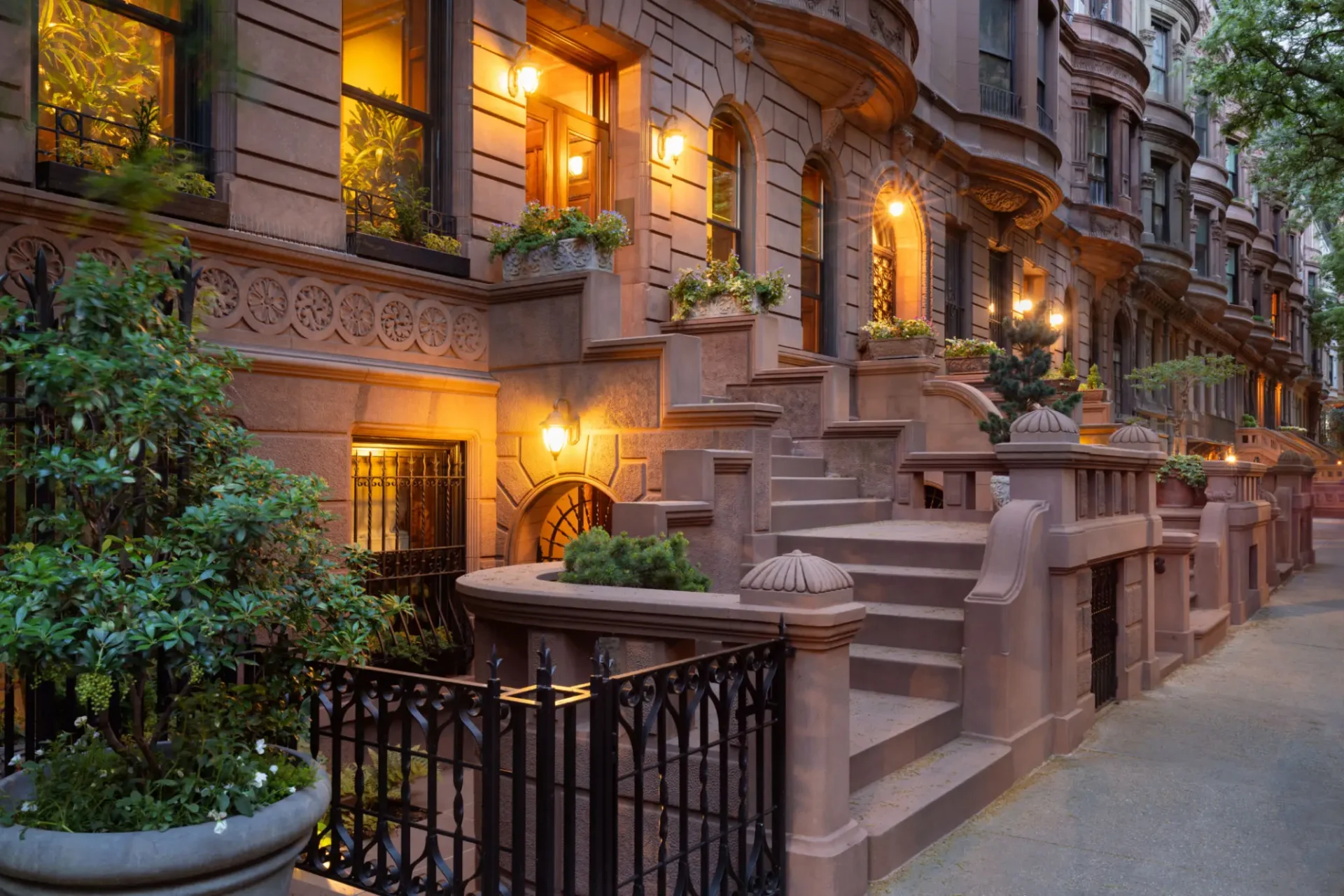 Warmly lit brownstone entrance with ornate architecture at dusk.