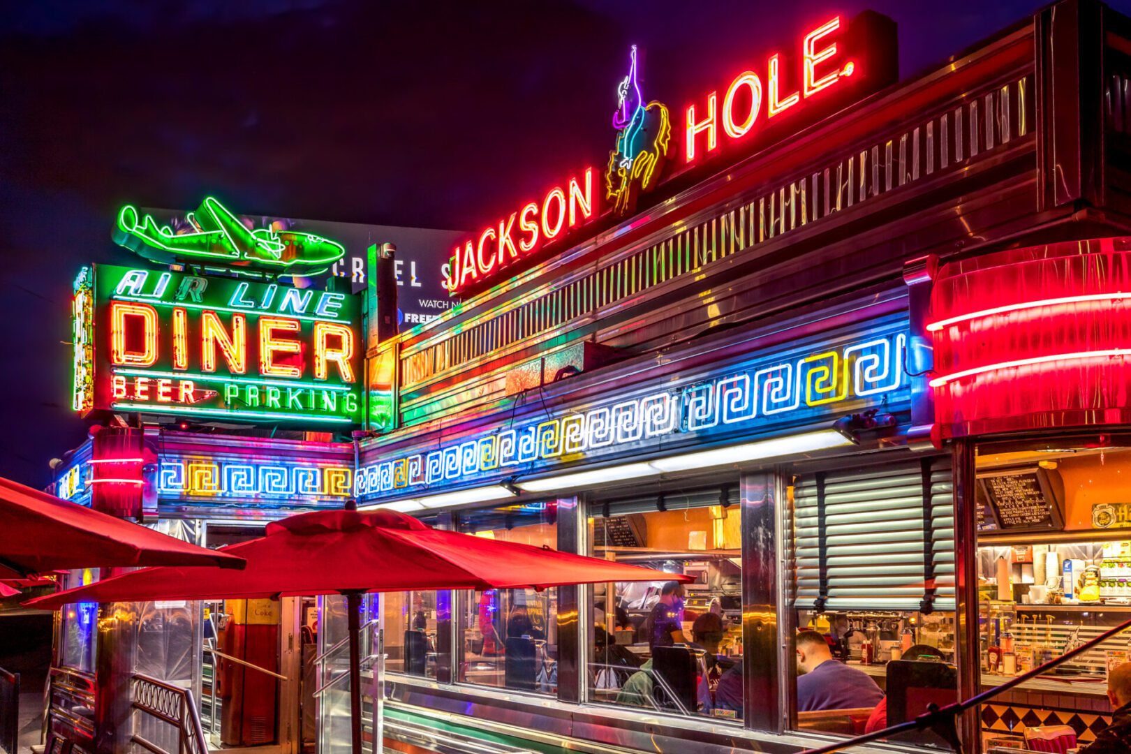 Vibrant neon signs illuminate a lively street at night.